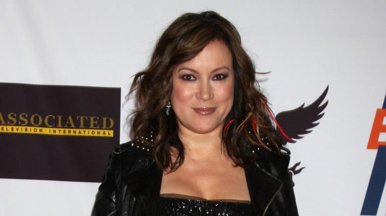 Jennifer Tilly posing in jacket and black dress