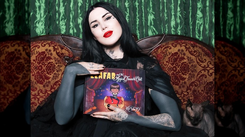 Kat Von D holds up her book