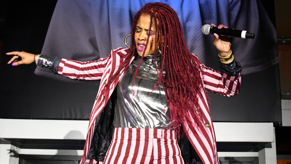 Kelis performing on stage in a striped suit