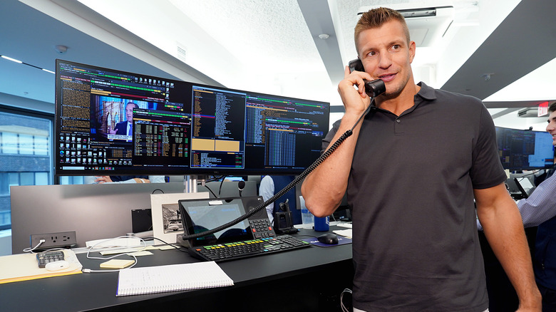 Rob Gronkowski wearing a grey polo shirt while talking on the phone