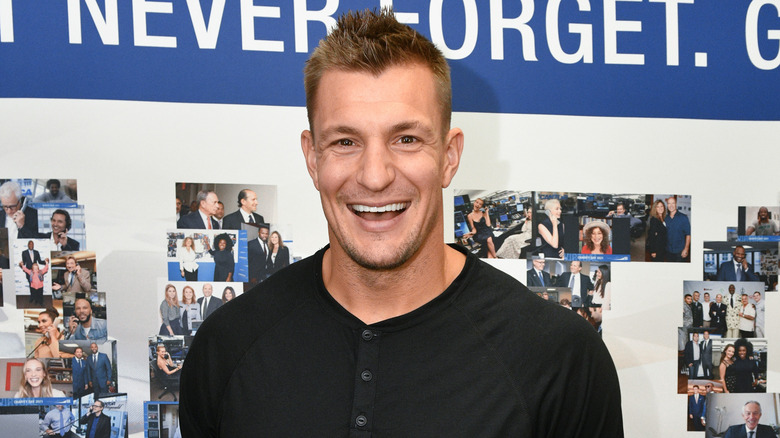 Rob Gronkowski smiling wearing a black button-down t-shirt