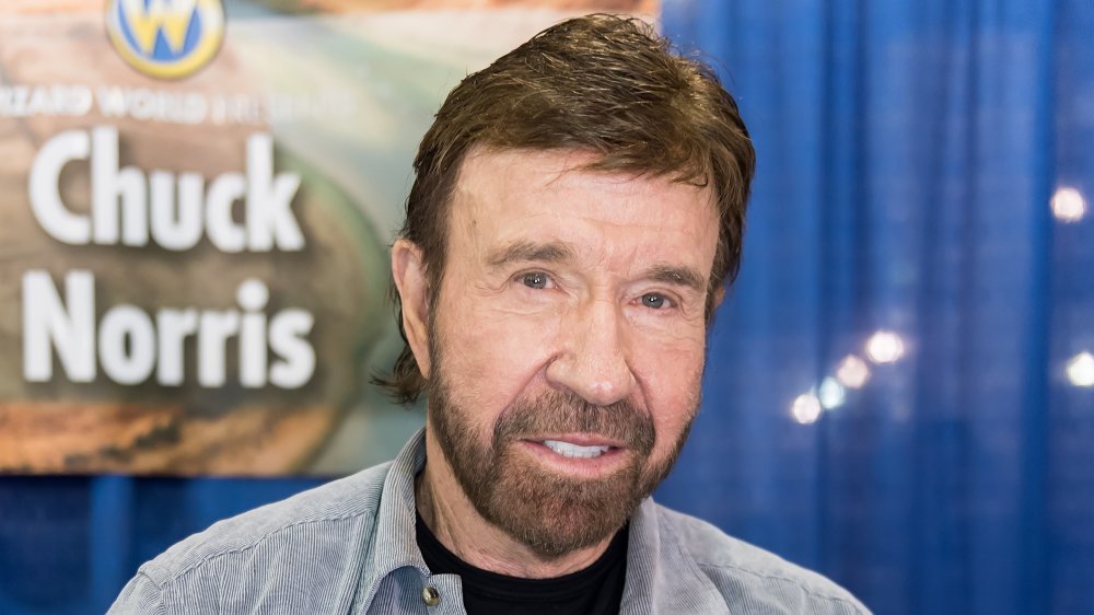 Chuck Norris smiling in front of Chuck Norris sign