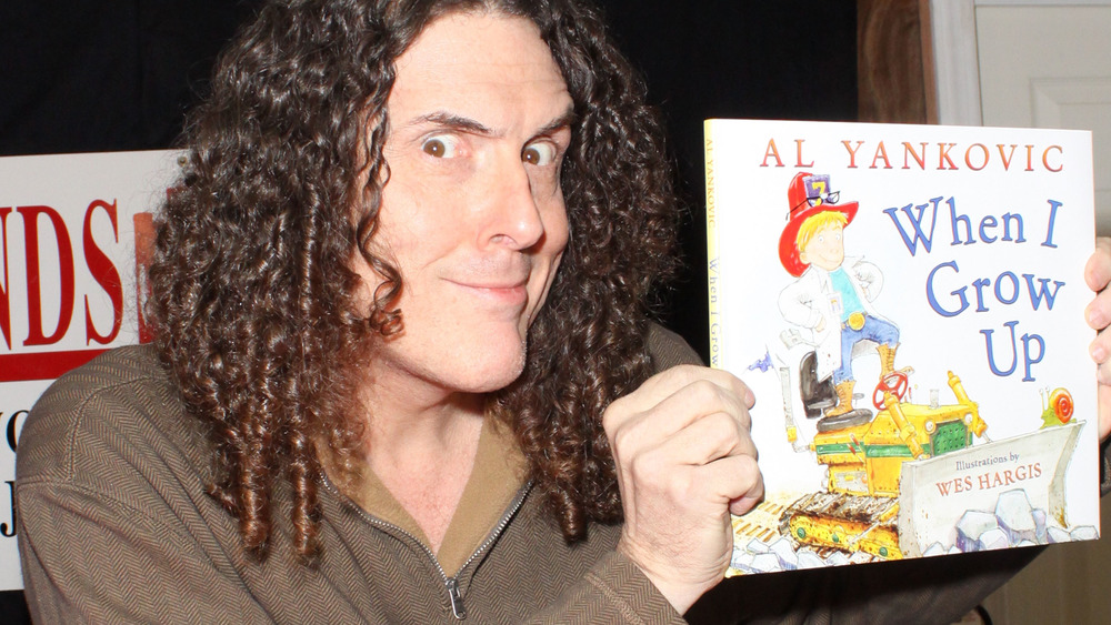 "Weird Al" Yankovic holding up his book