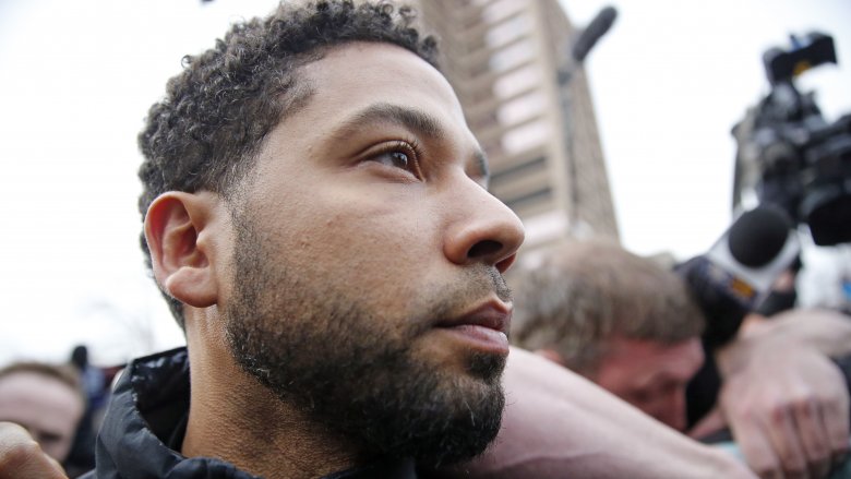 Jussie Smollett profile, looking serious while surrounded by reporters