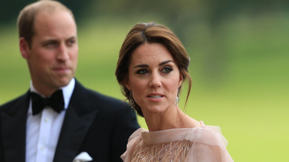 Kate Middleton with a serious expression, Prince William in the background