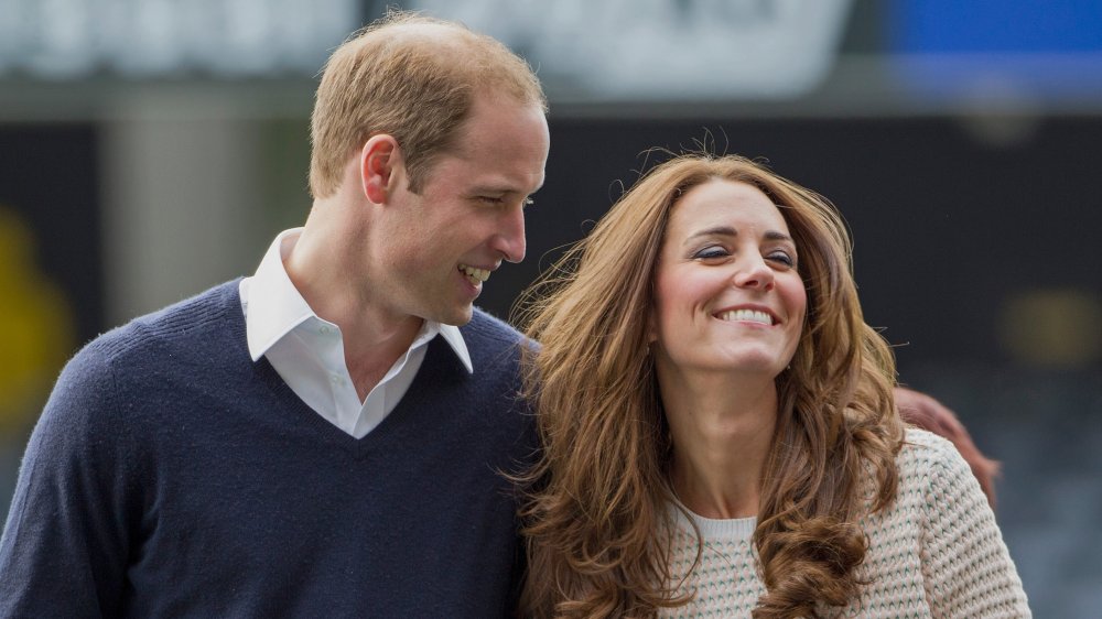 Prince William and Kate Middleton smiling while walking arm in arm