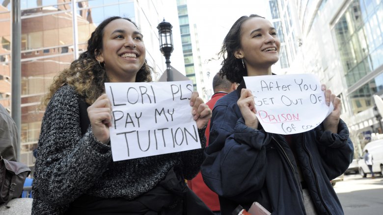 Mackenzie Thomas and Vivi Bonomie hold signs outside the courthouse where actress Lori Loughlin faces charges