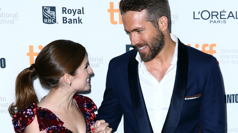 Anna Kendrick and Ryan Reynolds smiling at each other