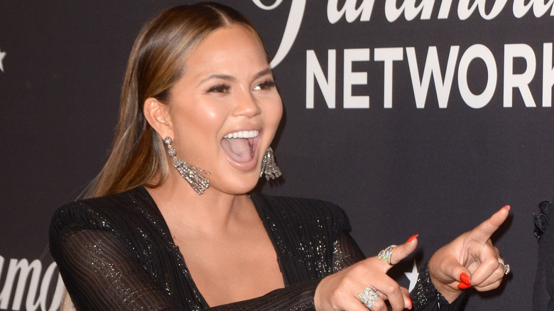 Chrissy Teigen pointing and laughing