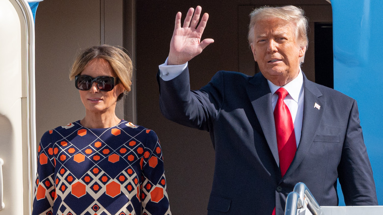 Donald Trump waving as Melania Trump poses