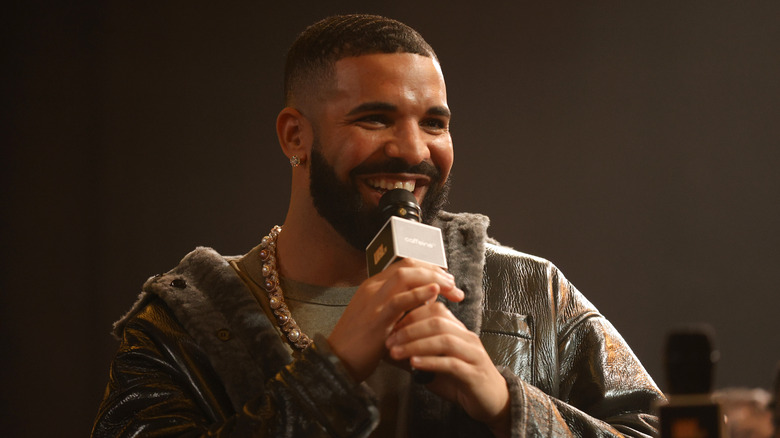 Drake smiling with a microphone