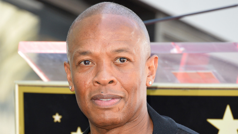 Dr. Dre wears stud earrings and poses