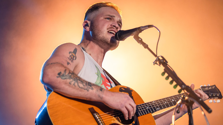 Zach Bryan singing into a mic 