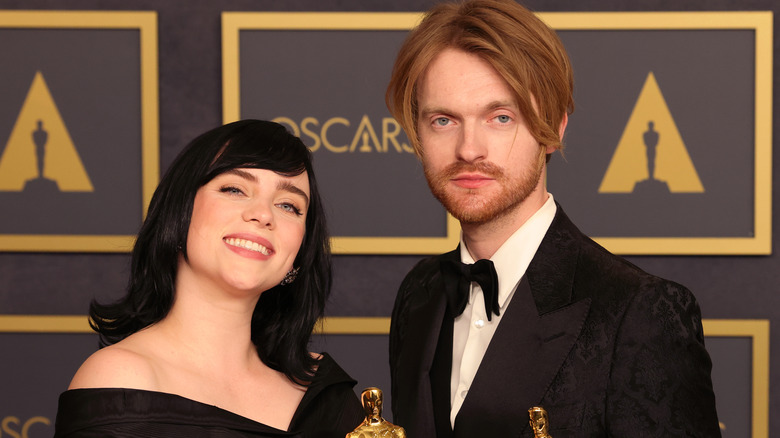 Billie Eilish  and Finneas O'Connell stand together at Oscars red carpet