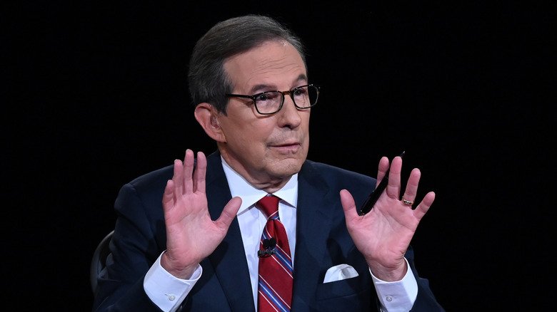 Chris Wallace moderating a debate with his hands raised