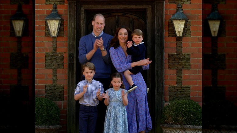 Prince William, Kate Middleton, and their kids stand at cottage door