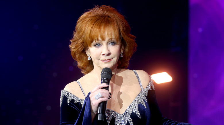 Reba McEntire speaking into microphone in blue gown