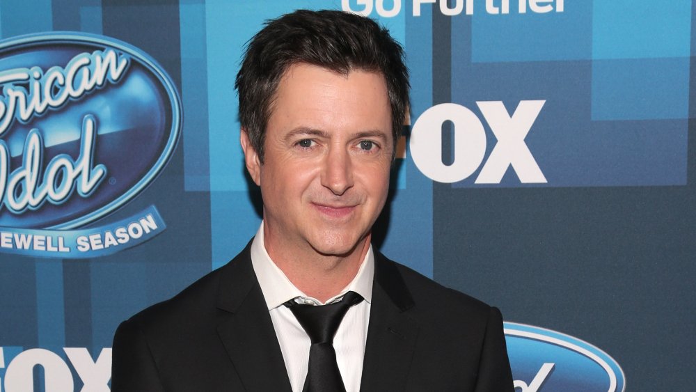 Brian Dunkleman standing in front of American Idol wall