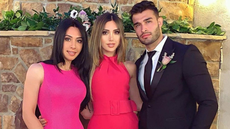 Sam Asghari posing with two sisters