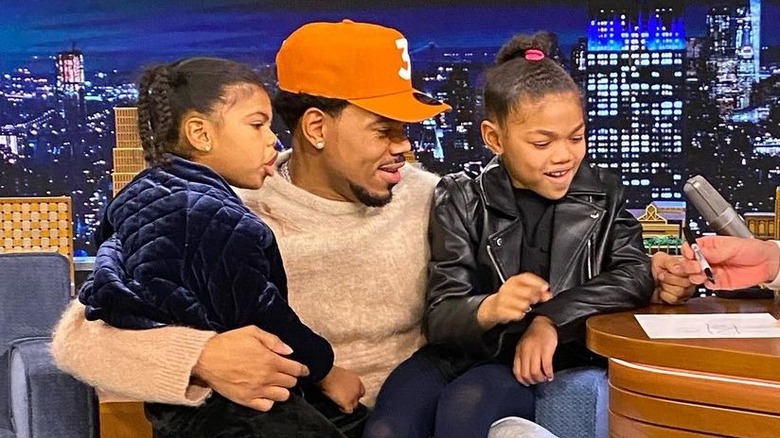 Chance the Rapper sits with his two daughters on his lap