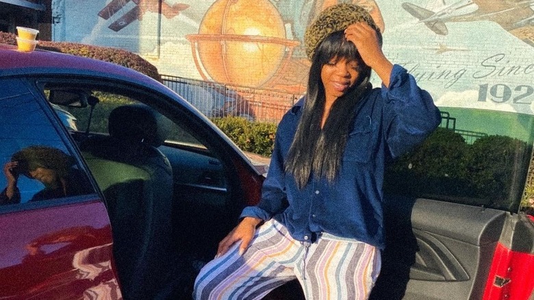 Joann Kelly, posing beside a car