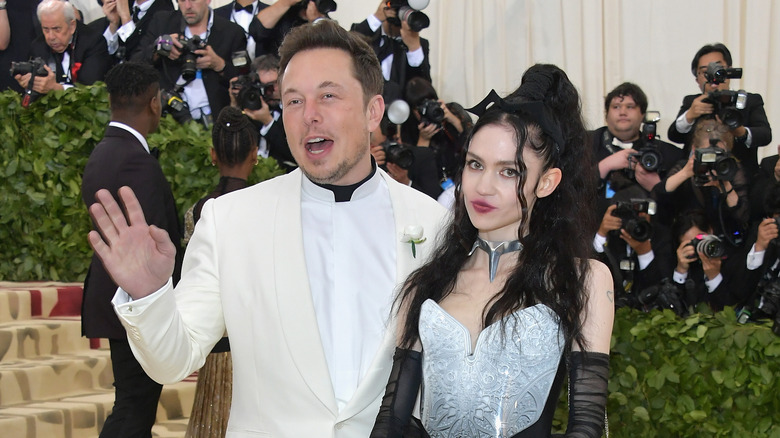 Elon Musk hand up Grimes silver dress