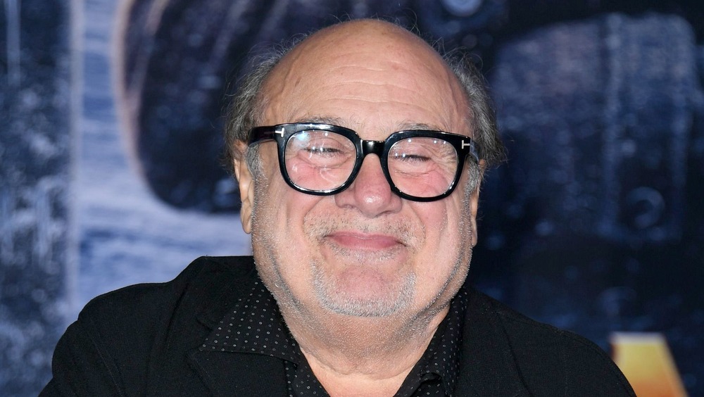 Danny DeVito smiling while wearing glasses