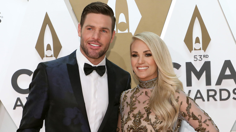 Carrie Underwood and Mike Fisher smiling on the red carpet