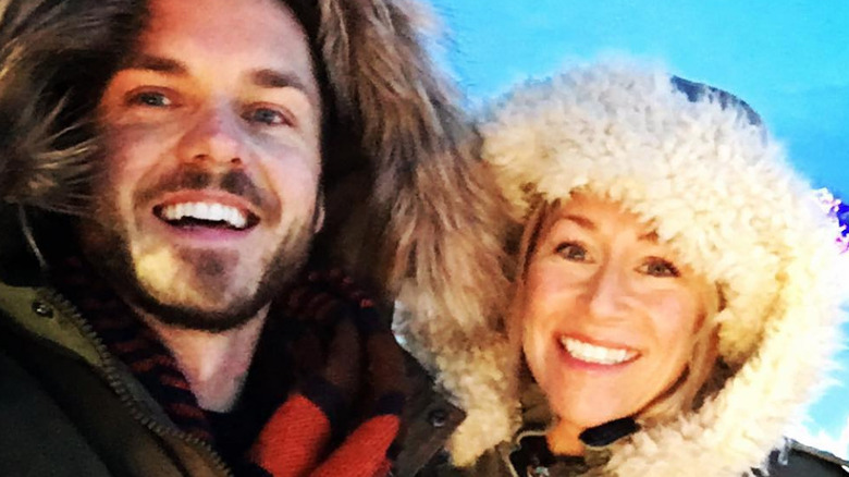 Paul Campbell and Lorie Metz smile for selfie wearing winter coats