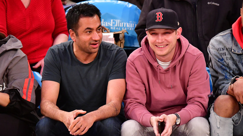 Kal Penn smiling with his partner Josh at a basketball game