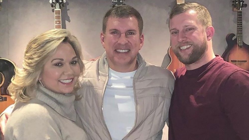 Julie Chrisley, Todd Chrisley, and Kyle Chrisley embracing and smiling 