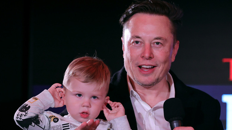 Elon Musk smiling holding baby boy