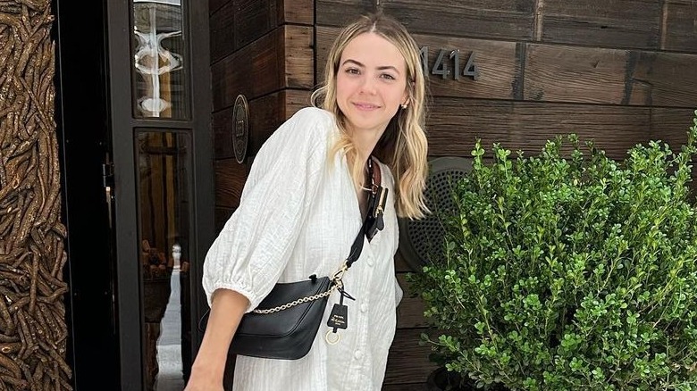 Bobbi Althoff posing in white dress and black crossbody bag