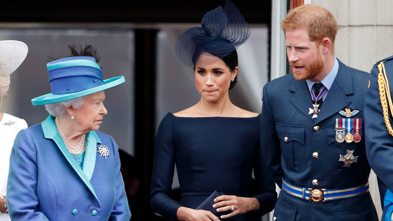 Queen Elizabeth II, Meghan, Duchess of Sussex and Prince Harry, Duke of Sussex watching a flypast