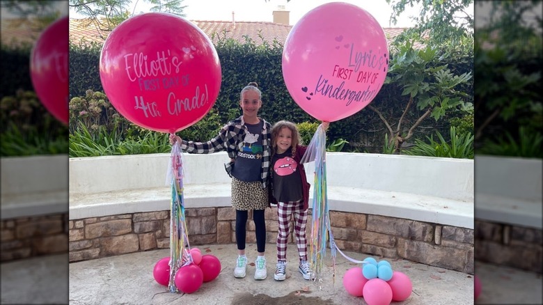 Elliott and Lyric McLean smiling and holding giant pink balloons