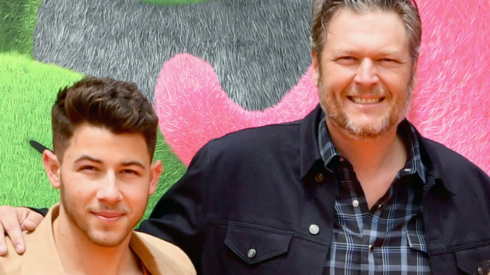 Nick Jonas and Blake Shelton smiling on the red carpet