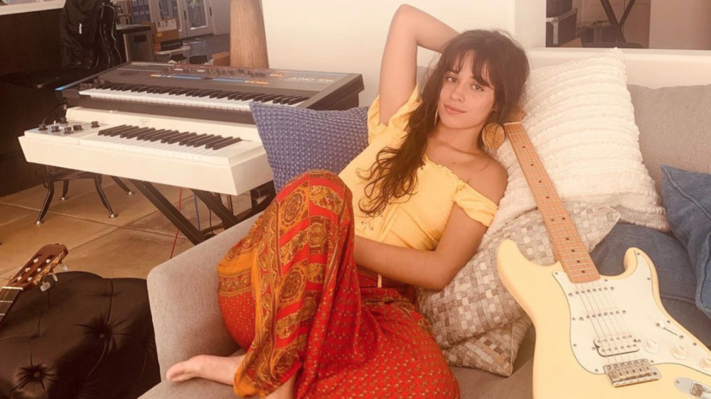 Camila Cabello poses on a couch 