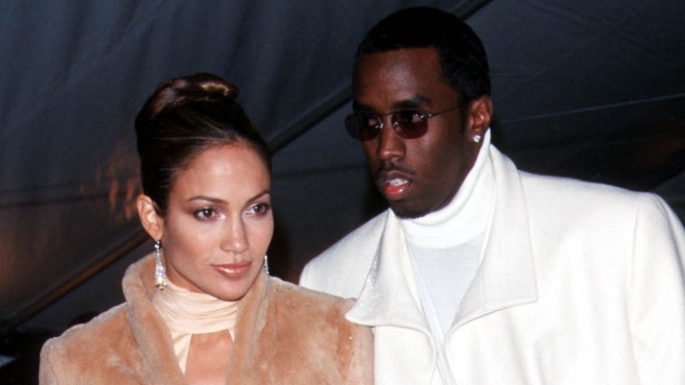 Jennifer Lopez in a beige fur coat, Sean Combs in a white pea coat, standing at a 1999 Met Gala event
