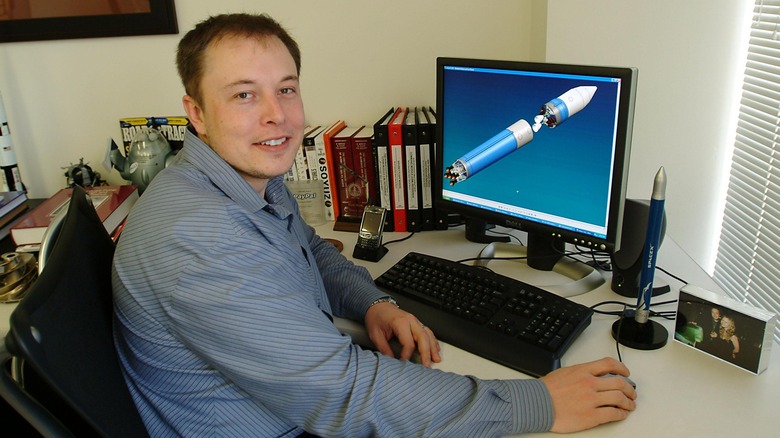 Elon Musk sitting at desk with computer