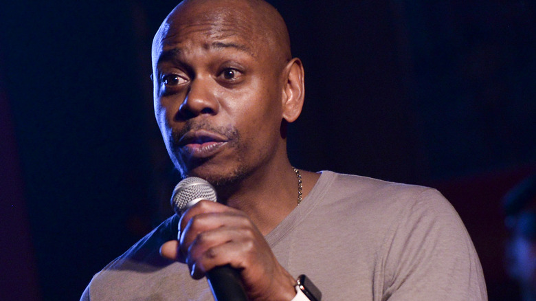 Dave Chappelle speaks into a mic