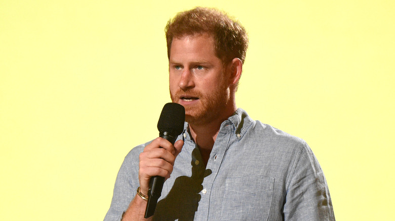 Prince Harry speaks into microphone onstage