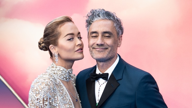  Rita Ora leaning over to kiss a smiling Taika Waititi 