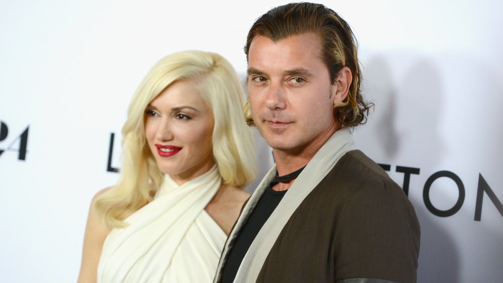 Gwen Stefani smiling in a white crop-topped dress, and Gavin Rossdale with a serious expression in a brown blazer