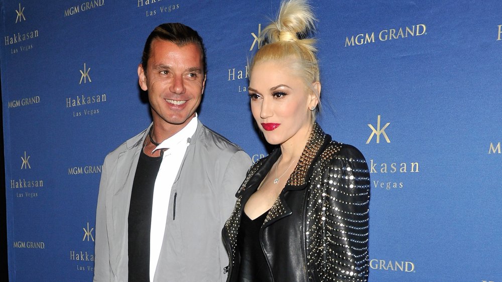 Gavin Rossdale smiling and wearing a grey jacket, and Gwen Stefani in black leather jacket with a neutral expression, posing together