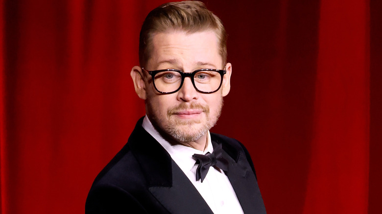 Macaulay Culkin posing for photographers in a tuxedo at a museum gala in 2024 in Los Angeles