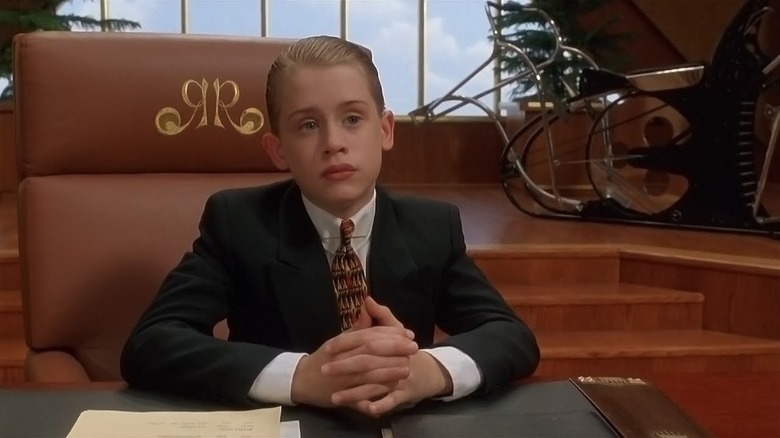 Richie Rich sitting at his desk with his hands clasped in Richie Rich