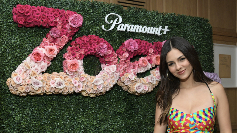 Victoria Justice posing in front of a Zoey 102 flower wall