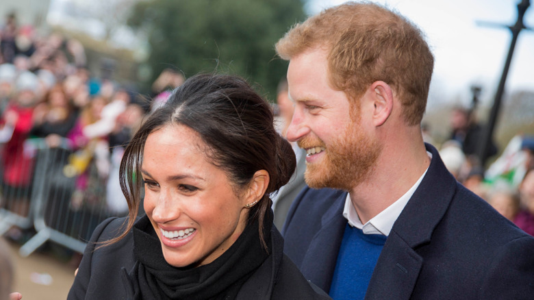 Prince Harry and Meghan Markle smiling in a crowd