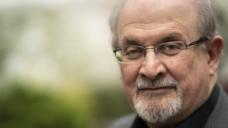 Salman Rushdie wearing clear glasses with gray goatee beard