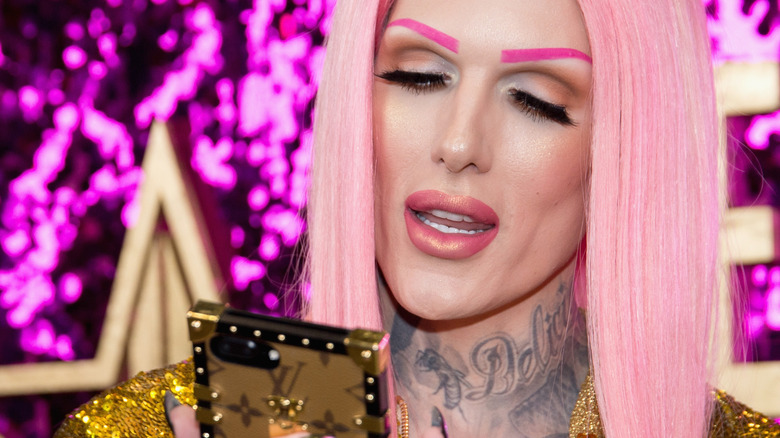 Jeffree Star with pink hair looking at a phone